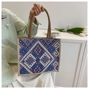 Close-up of geometric ethnic pattern weaving on a linen tote bag with brown handles