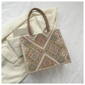 Detailed top view of a geometric woven tote bag with brown braided handles and soft texture