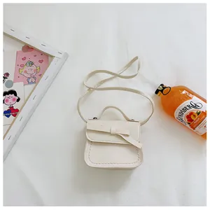 Flat lay of cream mini bow shoulder bag in faux leather with fine stitching details