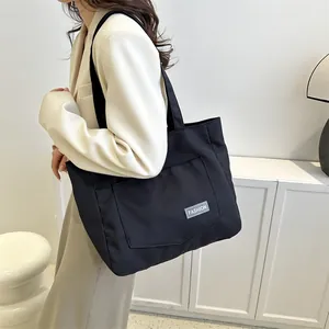 Minimalist black canvas tote bag with fashion label shown in a stylish indoor setting