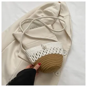 Detailed weave of beige and brown woven round bag with a faux pearl clasp and rope strap
