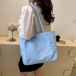 Light blue large capacity canvas tote bag with fashion label shown in a lifestyle setting
