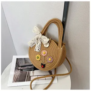 Brown round woven straw bag with colorful daisy flowers and white lace bow detail