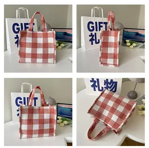 Détails du sac cabas en toile à carreaux rouges et blancs avec deux poignées sur un bureau
