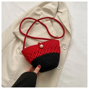 Close-up of red and black woven bag featuring a pearl clasp on a white blazer background
