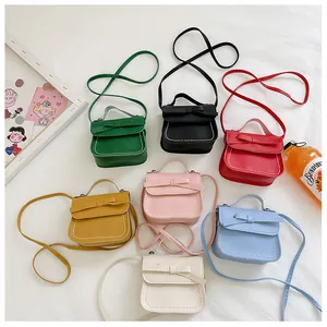 Flat lay of colorful mini bow purses for girls in six vibrant shades on a textured cloth