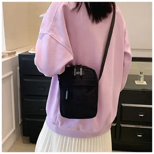 Detail view of a black corduroy crossbody bag worn over a casual outfit for daily styling