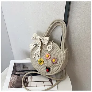 Round beige woven crossbody straw bag with colorful daisy embroidery and lace bow