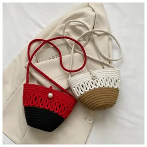 Detail of hand-woven crossbody straw bags with wavy texture and pearl closure button