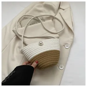Detail of two-tone woven bucket bag featuring a large pearl clasp and rope shoulder strap