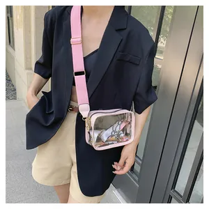 Outdoor shot of a transparent PVC crossbody bag with pink strap and interior silk scarf
