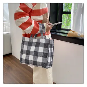 Détail du sac cabas en toile montrant le motif à carreaux noir et blanc et sa texture