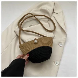 Detail of two-tone woven bucket bag with large pearl clasp and long shoulder strap