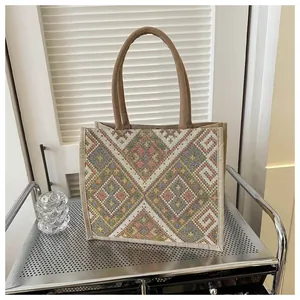 Close-up of bohemian geometric embroidery on linen tote bag with brown round handles