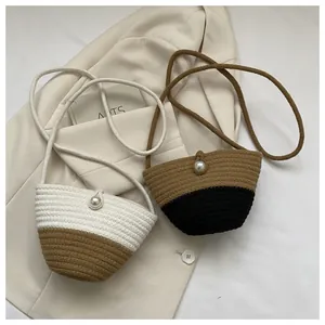 Detail view of woven crossbody straw bags featuring a pearl clasp and braided strap