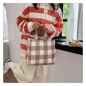 Détail du sac cabas en toile à carreaux marron et blanc avec des poignées solides