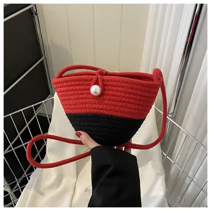 Detail of red and black woven bucket bag with pearl clasp and long rope shoulder strap