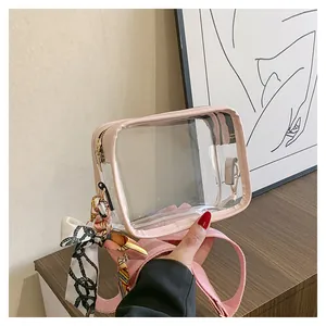Detailed shot of pink transparent PVC crossbody bag with silk scarf decoration and strap