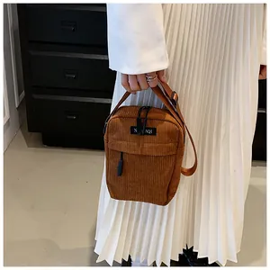 Detailed close-up of brown corduroy crossbody bag texture and NIAQI brand label