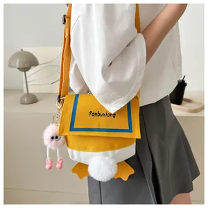Detail of yellow canvas crossbody bag with contrast trim and cute plush charm on strap