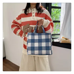 Détail du sac cabas en toile à carreaux bleu et blanc avec des poignées en tissu