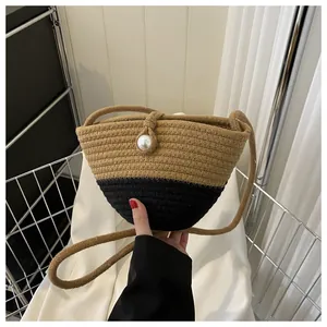 Detail of woven straw bag showing two-tone contrast and elegant pearl buckle closure