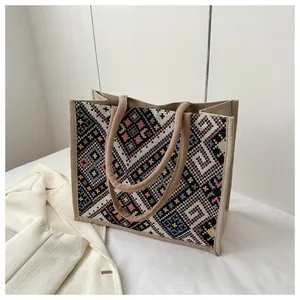 Close-up of bohemian woven tote bag showing multi-color geometric patterns and rope handles