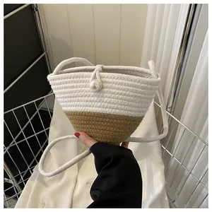 Close-up of woven bucket bag with pearl button closure and stylish cream two-tone design