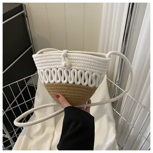 Detail of woven straw crossbody bag with white cotton cord, camel base and large pearl clasp