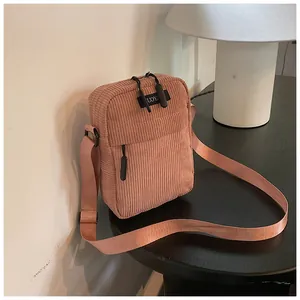 Detail of pink corduroy crossbody bag with double zippers and adjustable strap