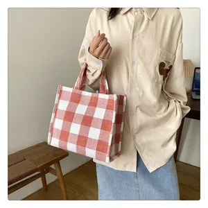Détail du sac cabas en toile à carreaux orange avec anses tissées dans un décor intérieur
