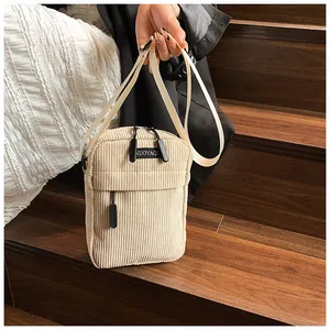 Detail shot of corduroy crossbody bag texture and dual zipper closure in beige
