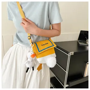 Detail of cute yellow duck canvas crossbody bag with plush charm and orange webbed feet