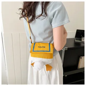 Detail view of the yellow canvas crossbody bag featuring a cute plush duck tail and webbed feet