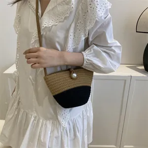 Summer straw woven bucket bag with contrast black base and white pearl closure detail
