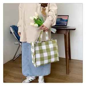 Détail d'un cabas en toile à carreaux verts tenu par un mannequin près d'un bureau