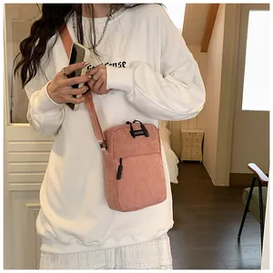 Pink corduroy crossbody bag detail featuring a front zipper pocket and adjustable strap