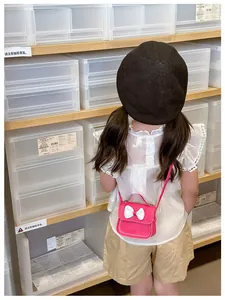 Vue détaillée de dos d'un enfant portant le mini sac à main rose avec un nœud blanc