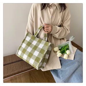 Sac fourre-tout en toile à damier vert tenu par un mannequin dans un décor extérieur