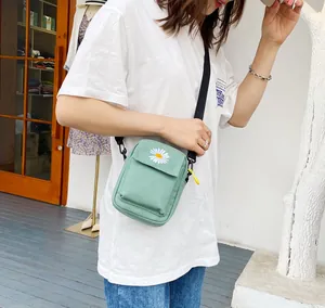 Borsa a tracolla in tela verde menta con ricamo a margherita e cinturino su un modello