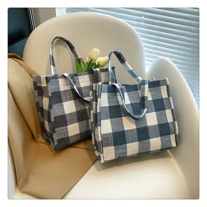 Détail du sac cabas en toile à carreaux bleus et blancs avec tulipes sur une chaise blanche
