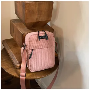 Close-up of pink corduroy crossbody bag texture with adjustable strap and front pocket
