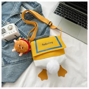 Detail of cute duck canvas crossbody bag with fluffy tail and burger pendant accessory