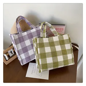 Texture détaillée des sacs en toile vichy violets et vert olive sur surface en bois