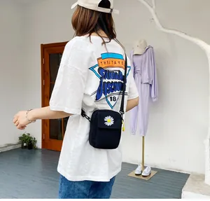 Dettagli della tracolla in nylon e ricamo a margherita su piccola borsa di tela nera