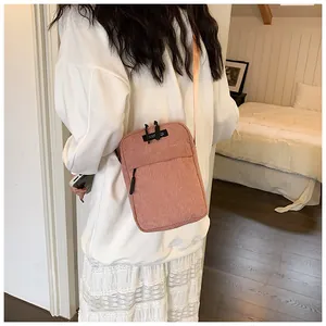 Detail of pink corduroy crossbody bag featuring RUOQI logo patch and black zipper strap