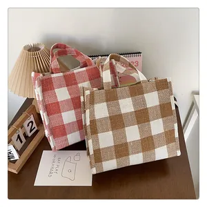 Vue détaillée de sacs cabas en toile à carreaux rétro rouge et marron sur bois