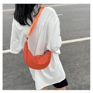 Vista street style di una borsa a tracolla a mezzaluna in nylon arancione acceso su modella