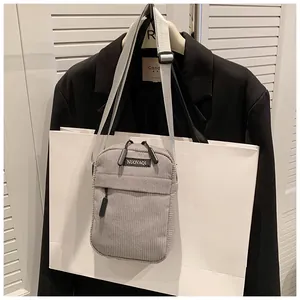 Detailed close-up of gray corduroy crossbody bag with adjustable strap and front zipper