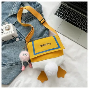 Flat lay of a cute yellow duck canvas bag with orange feet and plush charm details